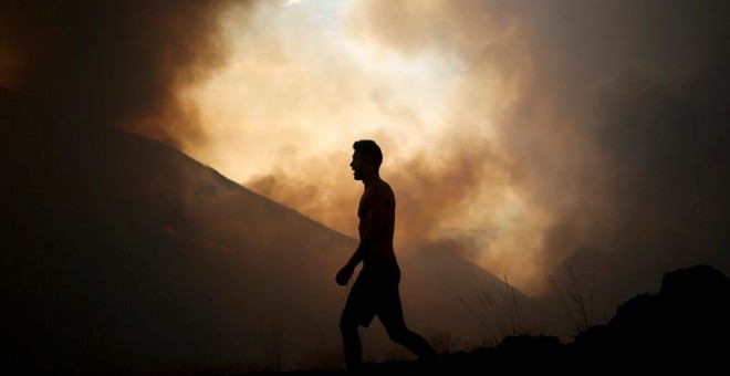 Un ciudadano observa un incendio forestal producido en la localidad Cortegaça de Arouca, Portugal. EFE/Estela Silva