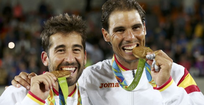 Los tenistas españoles Rafael Nadal y Marc López muerden la medalla de oro ganada hoy en la final de tenis de dobles masculino en los Juegos Olímpicos de Brasil 2016. REUTERS/Kevin Lamarque
