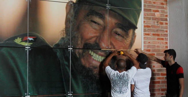 Varios operarios instalan un retrato del líder de la revolución cubana, Fidel Castro, que cumple 90 años. REUTERS/Stringer