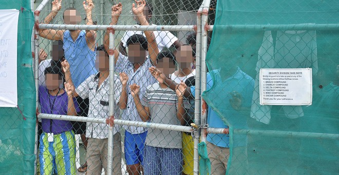 Refugiados miran desde la valla del centro de detención en la Isla de Manus.  REUTERS