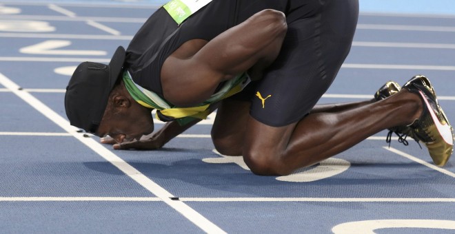 El atleta jamaicano Usain Bolt besa la pista tras ganar en Rio su novena medalla de oro en unos JJOO. REUTERS/Phil Noble