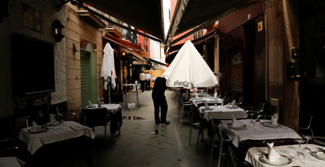 Un camarero abre una sombrilla en una terraza de un bar en Sevilla. REUTERS