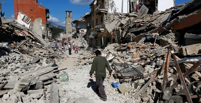 Un hombre camina entre los restos de los edificos derruidos por el terremoto en Pescara del Tronto, Italia.  REUTERS/Remo Casilli