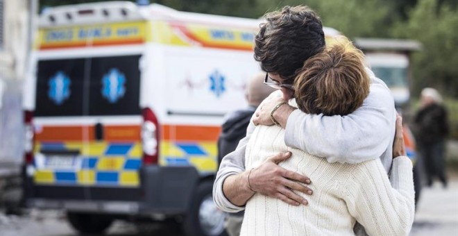 Dos personas se abrazan junto a una ambulancia tras el terremoto en la localidad de Fonte del Campo, cerca de Accumoli, en el centro de Italia.  EFE/Angelo Carconi