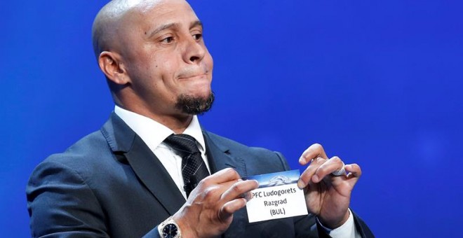 El ex jugador brasileño Roberto Carlos muestra la papeleta del Ludogorets Razgrad durante el sorteo de los emparejamientos de la fase de grupos de la Liga de Campeones. EFE/Sebastien Nogier