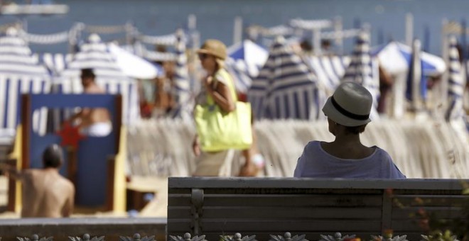 Una mujer descansa a la sombra en la playa de Ondarreta de San Sebastián, donde se registran altas temperaturas y los cielos permanecen despejados. EFE/Juan Herrero