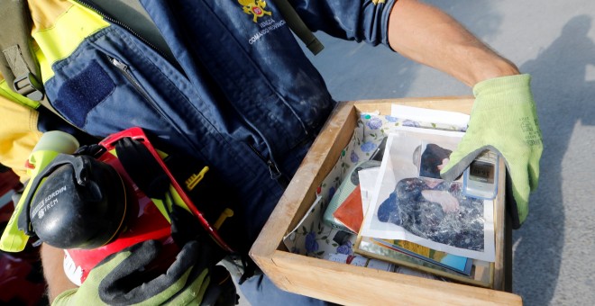 Un bombero que lleva un cajón con fotos y objetos personales después de un terremoto en Amatrice, el centro de Italia. REUTERS/Ciro De Luca