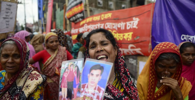 Una mujer con unas fotos de un conocido desaparecido en la tragedia de Rana Plaza. MUNIR UZ ZAMAN / AFP