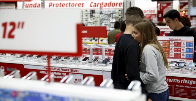 Unos jóvenes comprando en una tienda de equipos de informática, en Madrid. REUTERS