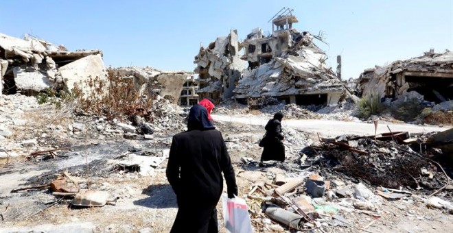 Mujeres sirias caminan entre las ruinas de la ciudad Homs, Siria. EFE/Youssef Badawi