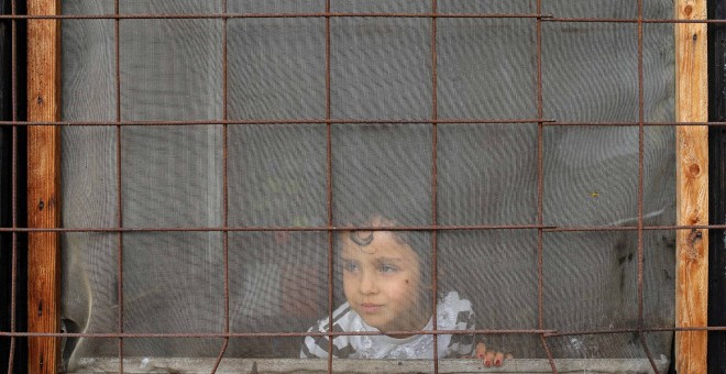 Una niña mira a través de una ventana en un campo de refugiados situado en el suburbio de Krnjaca, en Belgrado (Serbia), este miércoles. REUTERS/Marko Djurica
