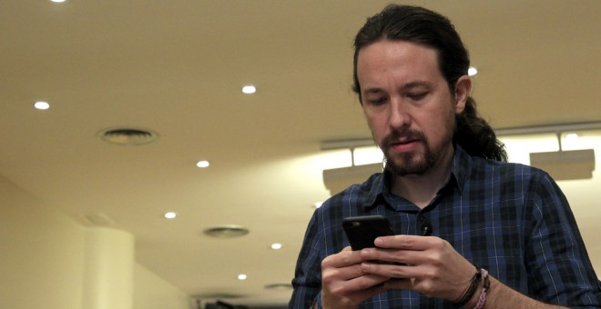 El secretario general de Podemos, Pablo Iglesias, mira su móvil poco antes de comparecer ante los medios de comunicación en el Congreso. EFE/Chema Moya