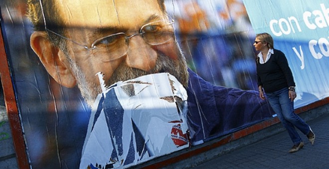 Una mujer camina ante una valla electoral con la imagen de Mariano Rajoy. / FOTO: MANUEL MARRAS