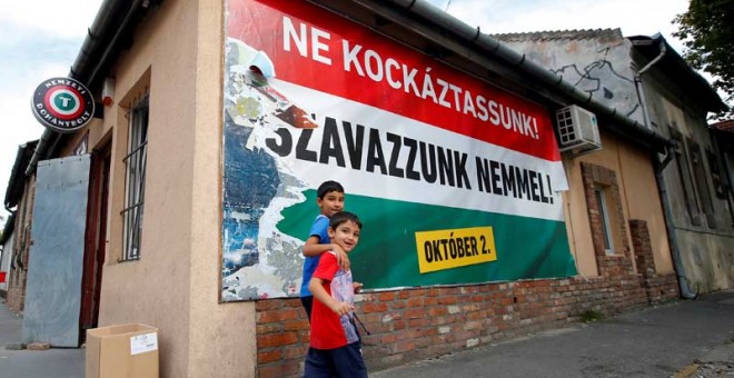 Dos niños inmigrantes pasan ante un cartel en Budapest que pide el 'No' en la consulta sobre migración. / REUTERS