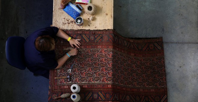 Un restaurador repara con métodos artesanales una alfombra en la Real Fábrica de Tapices. REUTERS / Susana Vera