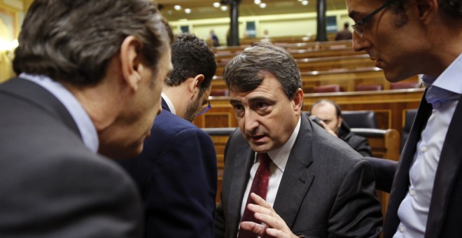 El portavoz parlamentario del PNV, Aitor Esteban, conversa con el portavoz del Grupo Popular, Rafael Hernando, en presencia del diputado socialista Eduardo Madina, durante el pleno del Congreso. EFE/Mariscal