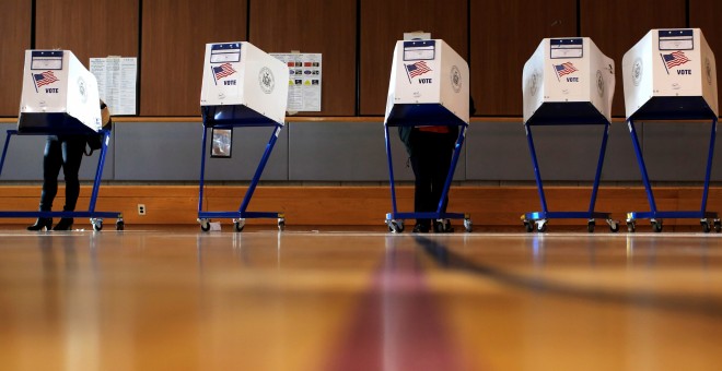 Varios votantes preparan su voto en las cabinas de un colegio electoral en el barrio neoyorquino de East Harlem. REUTERS/Andrew Kelly