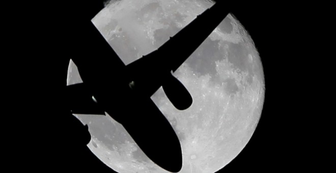 Un avión de pasajeros surca el cielo frente a la superluna en España. REUTERS/Jon Nazca