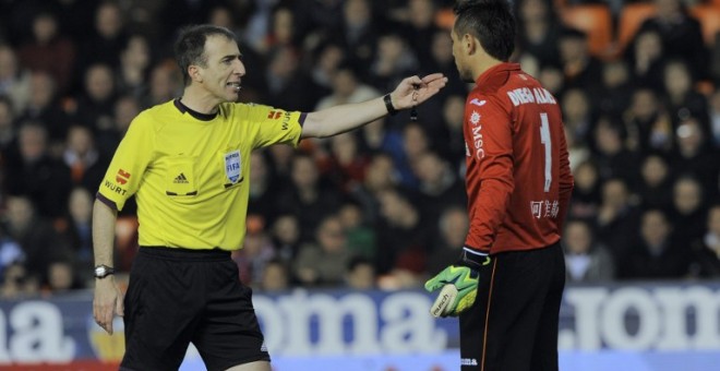 El árbitro David Fernández Borbalán ante el portero Diego Alves en un partido de Liga en 2014. /AFP