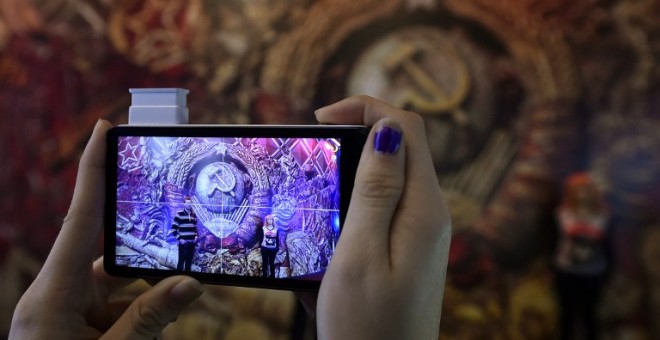 Una mujer toma una imagen de un emblema de la URSS durante una exposición en Moscú. - AFP