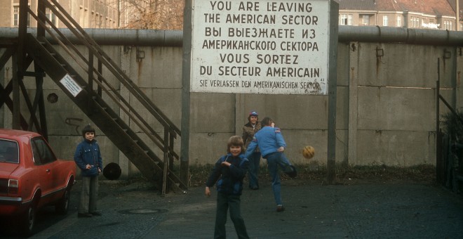 Niños jugando al fútbol ante el Muro de Berlín.