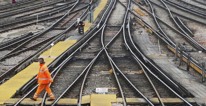 Un trabajador atraviesa las vías de la estación ferroviaria de Clapham Junction, en Londres. REUTERS/Luke MacGregor