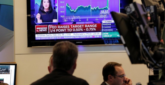 Los operadores de la bolsa de Wall Street observan un televisor en el patio de negociación, donde se informa de la subida de tipos en EEU. REUTERS/Lucas Jackson