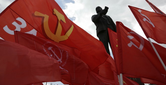 Miembros del Partido Comunista ondean sus banderas junto a una estatua de Vladimir Lenin en Simferopol, capital de Crimea. - AFP