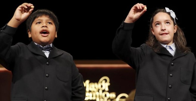 Los niños de San Ildefonso Nerea y Daniel muestran las bolas con el primer cuarto premio que ha recaido en el número 59.444 del Sorteo Extraordinario de Navidad , que se desarrolla en el Teatro Real. EFE/Ballesteros