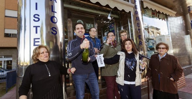 La vendedora de un quinto premio de la loteria de navidad, el número 22259, Carolina Abellán (2d), junto a su madre, dueña del la floristería y ferretería, Mari Carmen Espinosa (i), y su marido, Pedro Francisco Navarro (2i), celebran la venta del número a