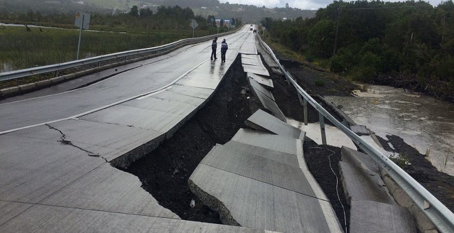 Personas caminan por una carretera destruida hoy, domingo 25 de diciembre de 2016, en Tarahuin, en la isla de Chiloe, localidad distante a 1.250 km. al sur de Santiago (Chile).