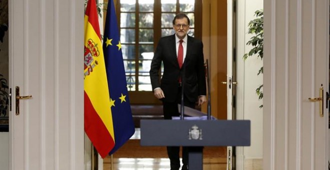 El presidente del Gobierno, Mariano Rajoy, se dirige a la sala del Palacio de la Moncloa. /EFE