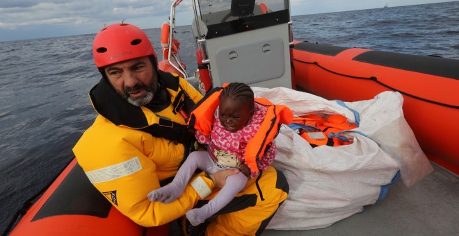 Un voluntario de Proactiva Open Arms rescata a un menor que iba junto a cientos de eprsonas en una bote hinchable en el Mediterráneo.- Una embarcación cargada de personas flota a la deriva en el Mediterráneo.- REUTERS/Yannis Behrakis
