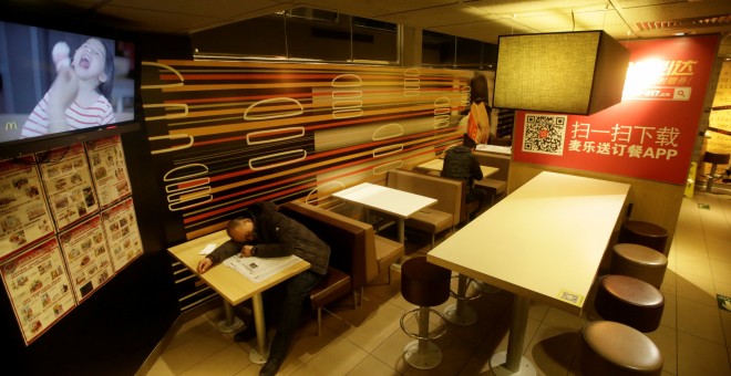 Un hombre dormido en una de las mesas de un restaurante de McDonald's en Pekín. REUTERS/Jason Lee