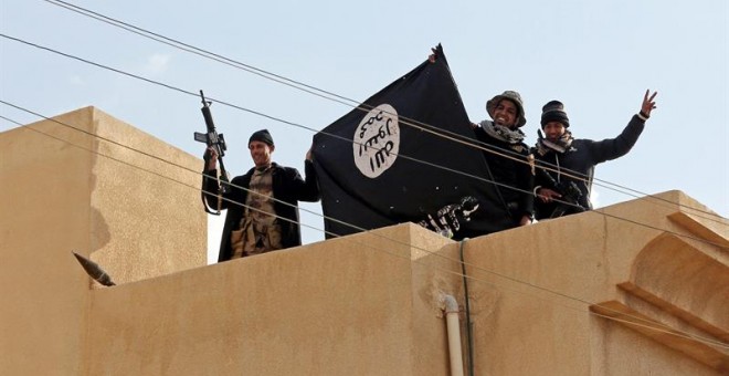 Soldados iraquíes muestran una bandera del Estado Islámico mientras toman posición en un tejado de una vivienda de Mosul. - EFE