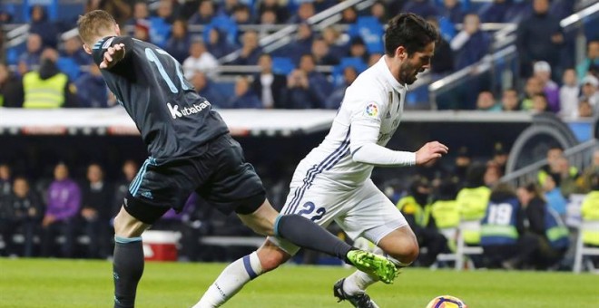 El centrocampista del Real Madrid, Francisco Alarcón 'Isco' (d), se lleva el balón ante el jugador de la Real Sociedad, David Zurutuza, durante el encuentro que han disputado esta noche en el estadio Santiago Bernabéu, en Madrid. EFE / J. P. Gandul