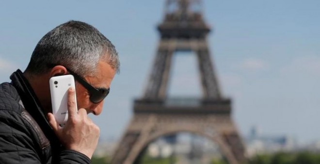 Un hombre habla por su móvil en la plaza parisina de Trocadero, con la Torre Eiffel al fondeo. REUTERS/Christian Hartmann