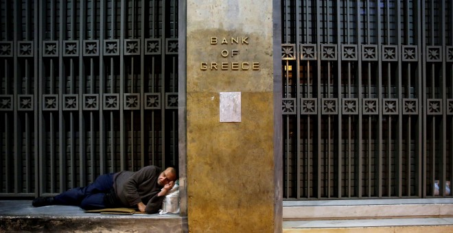 Un sintecho duerme a las puertas del Banco de Grecia en Atenas.REUTERS/Yannis Behrakis