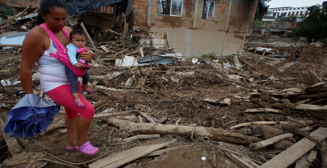 Una mujer con su niño camina entre los escombros de Mocoa. /REUTERS