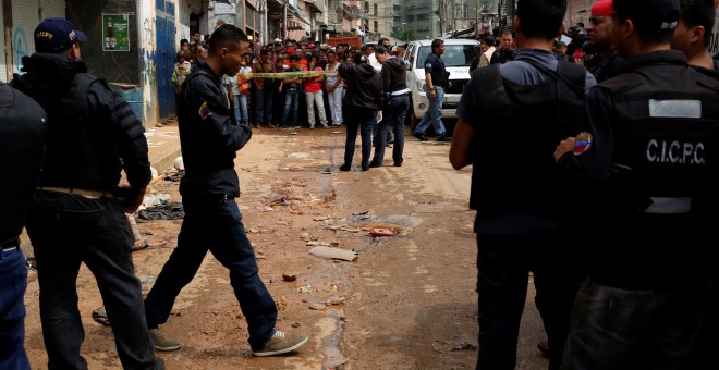 Policías e investigadores buscan evidencia frente a una panadería saqueada en Caracas. REUTERS / Carlos Garcia Rawlins