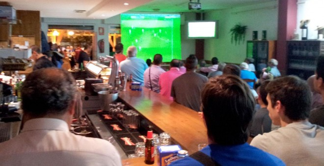 Clientes de un bar viendo un partido de fútbol por televisión.