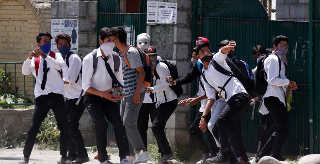 Estudiantes con el rostro cubierto lanzan piedras contra la policía india durante las priotestas en el estado de Cachemira. REUTERS/Danish Ismail