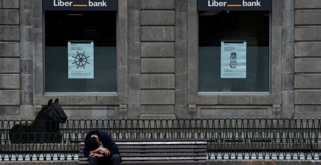 Un hombre sentado frente a la sede de Liberbank en Oviedo. REUTERS/Eloy Alonso