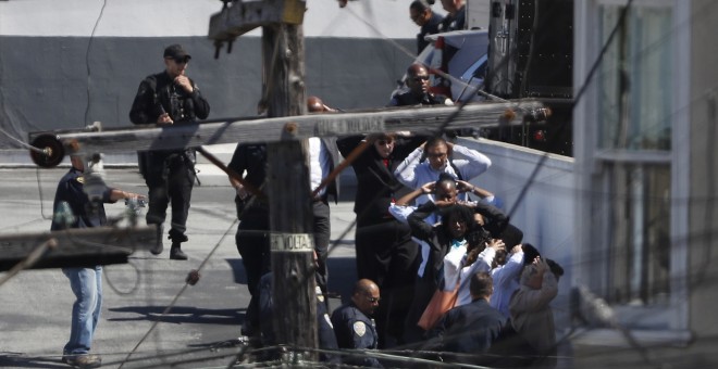 Las transeúntes  están siendo evacuados con las manos por encima de sus cabezas por orden de la policía en el área de un incidente de tiroteo en una instalación de United Parcel Service (UPS) en San Francisco, California, EE.UU. 14 de junio de 2017. REUTE