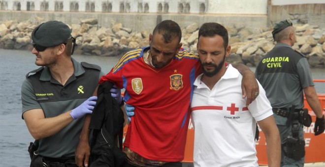 - Agentes de la Guardia Civil y personal de Cruz Roja ayudan, a su llegada al puerto de Tarifa (Cádiz), a uno de los 88 inmigrantes de origen subsahariano rescatados esta mañana por Salvamento Marítimo cuando trataban de alcanzar la costa española en tres