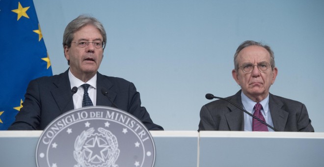 El primero ministro italiano, Paolo Gentiloni (i), con el ministro de Economía, Pier Carlo Padoan (d), en la comparecencia ante los medios en el Palacio Chigi, sede del Consejo de Ministros, para informar sobre la liquidacion de los banco Veneto Banca y P