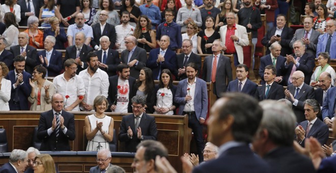 Los diputados de Unidos Podemos-En Comù Podem-En Marea, que se han levantado en el hemiciclo a la entrada de Felipe VI al acto del aniversario de las elecciones de 1977, pero no le han aplaudido, muestran claveles rojos para honrar a los 'héroes y heroína