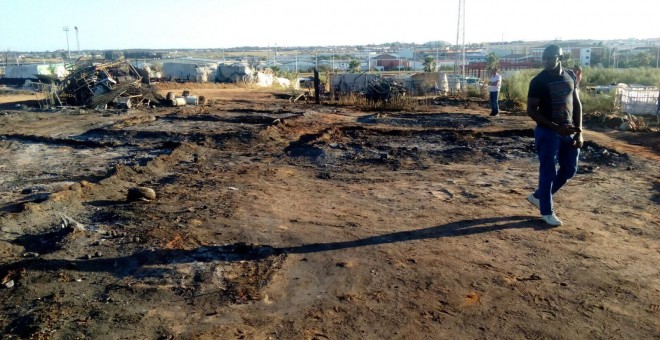 Un inmigrante pasea por una zona arrasada por el incendio en el asentamiento chabolista. /ANTONIO ABAD