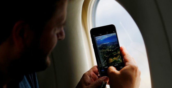 Un hombre toma una fotografía desde la ventalla de su asiento en un viaje en avión. REUTERS/Denis Balibouse