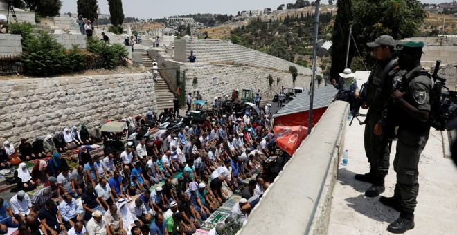 Agentes de policía  israelí montan guardia mientras los palestinos rezan en la Puerta del León, una entrada a la ciudad vieja de Jerusalén, en protesta por las nuevas medidas de seguridad de Israel en la mezquita al-Aqsa.- REUTERS